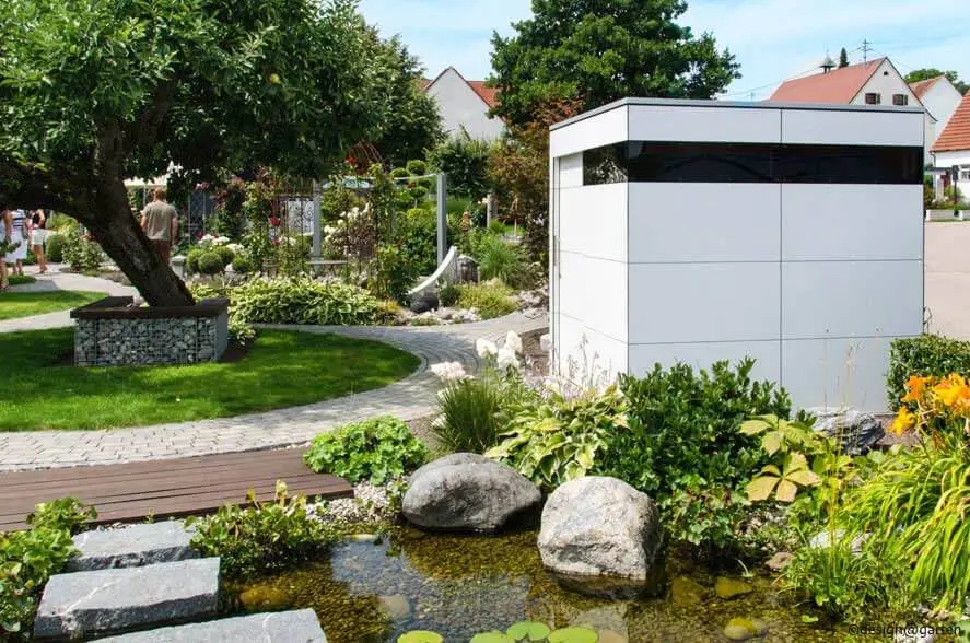 Abri de jardin blanc moderne dans un beau jardin avec étang.