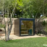 Schwarze Aussensauna aus HPL mit Hängematte im Garten unter Bäumen