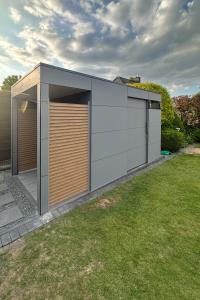 Gartenhaus in Grau mit Vordach und Sichtschutz