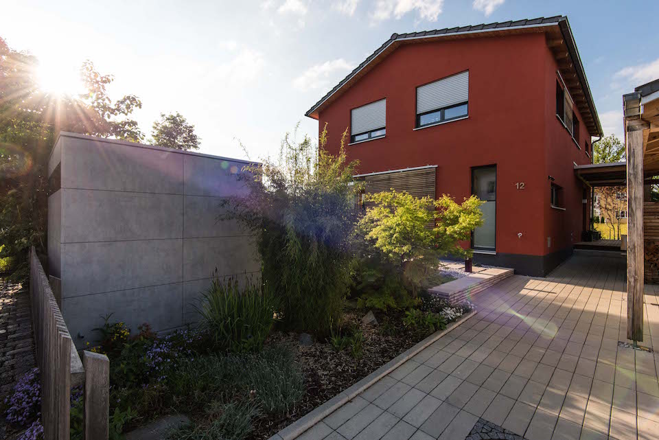 Gartenhaus in Sichtbeton Optik vor rotem Haus