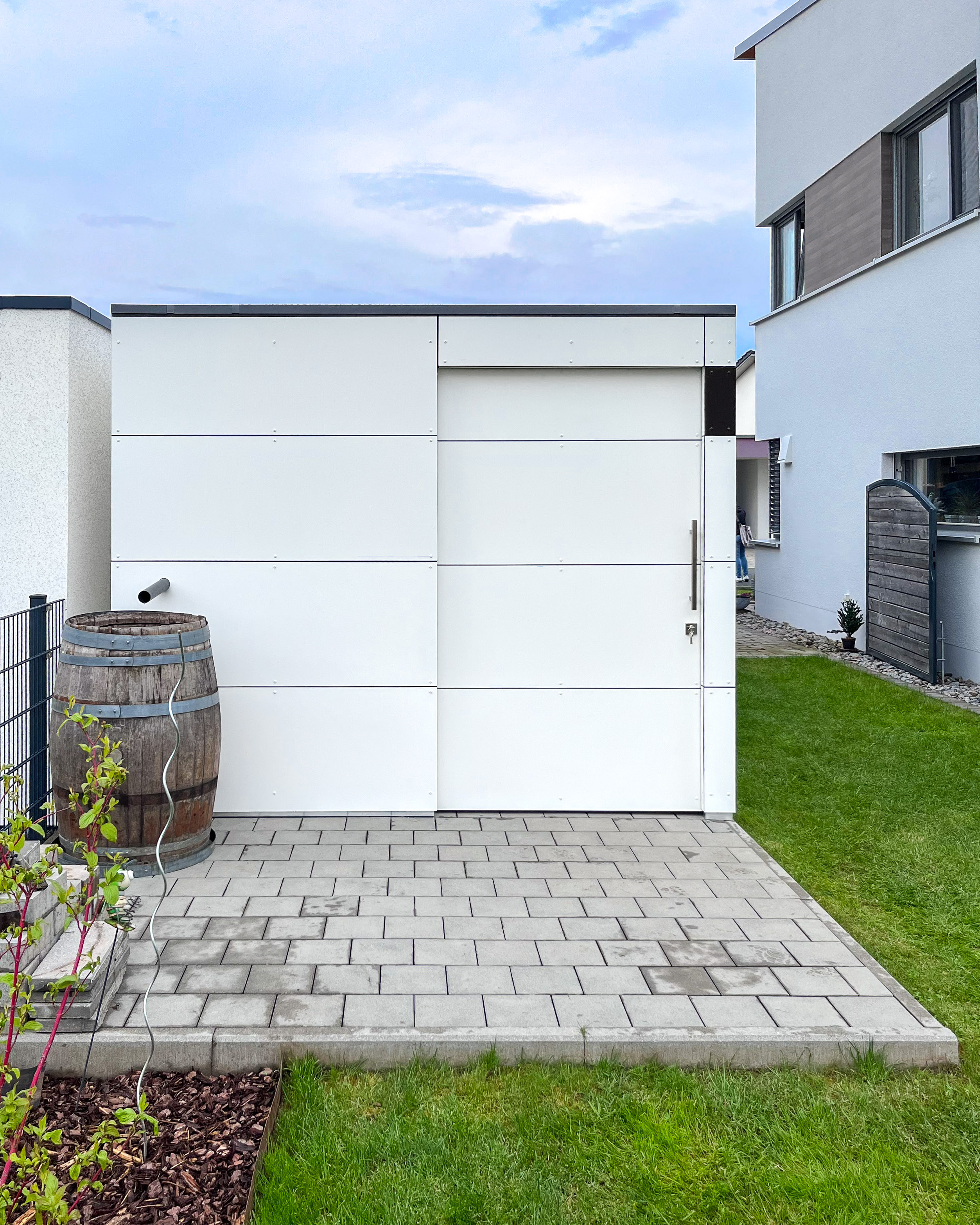 Stauraum neben der Garage mit weissem Gartenhaus