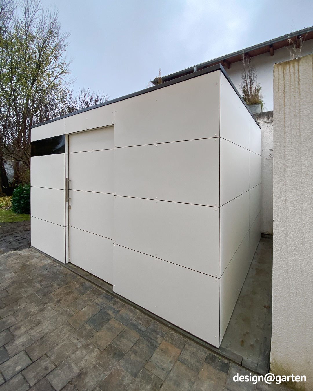 Weisses Gartenhaus als Stauraum-Erweiterung neben einer Garage