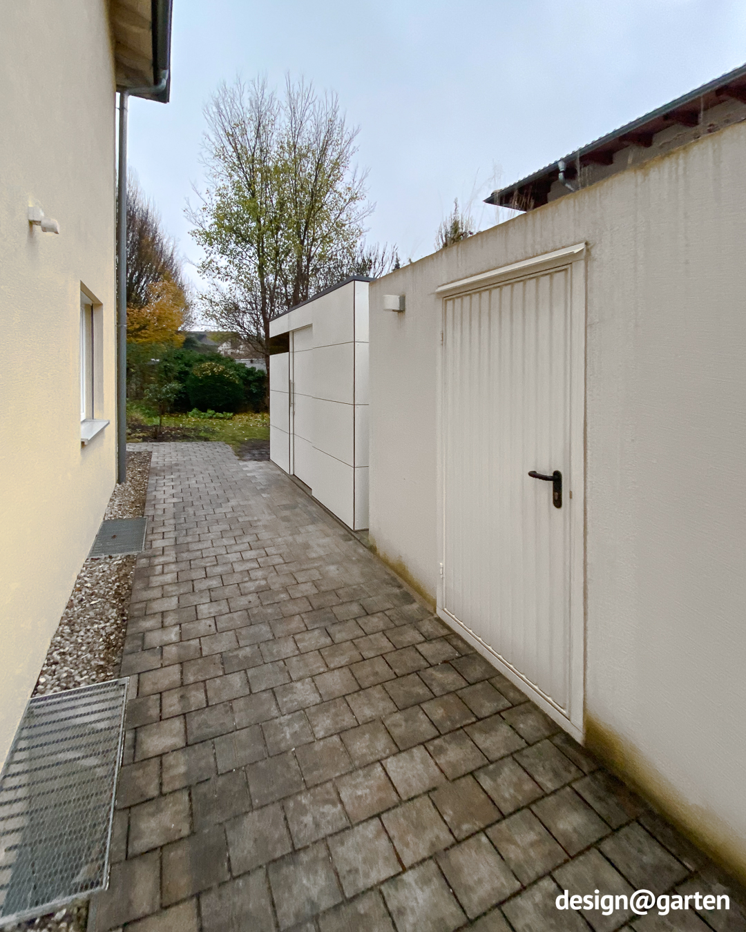 White garden shed as additional storage space next to a garage