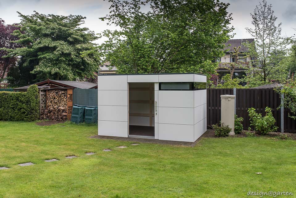 Contrastes dans le jardin : une cabane de jardin à toit plat en HPL rencontre le charme d'une maison de campagne