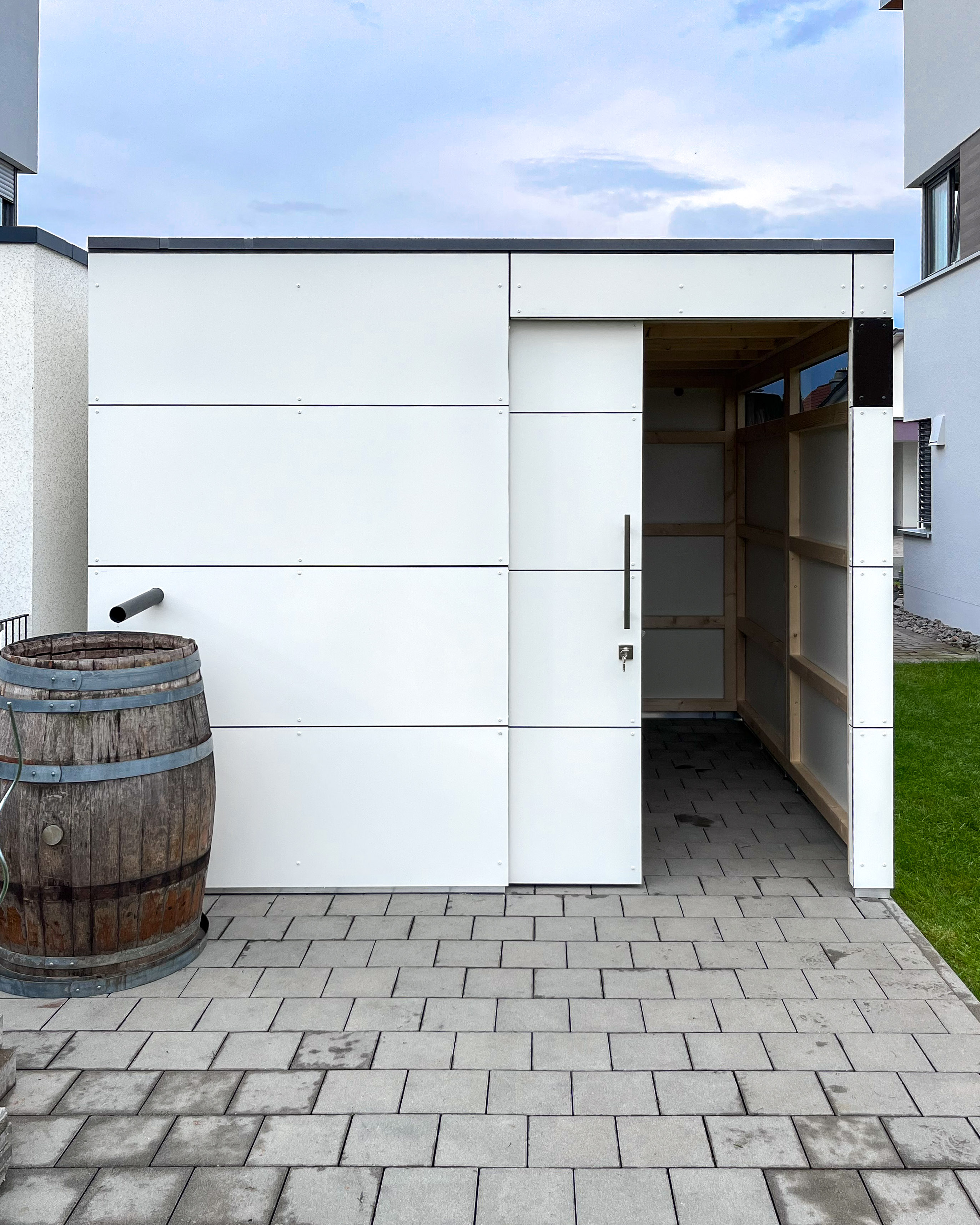 Espace de rangement à côté du garage avec abri de jardin blanc