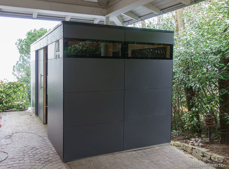 Lavoro su misura sotto il posto auto coperto: la casetta da giardino di design come miracolo di integrazione