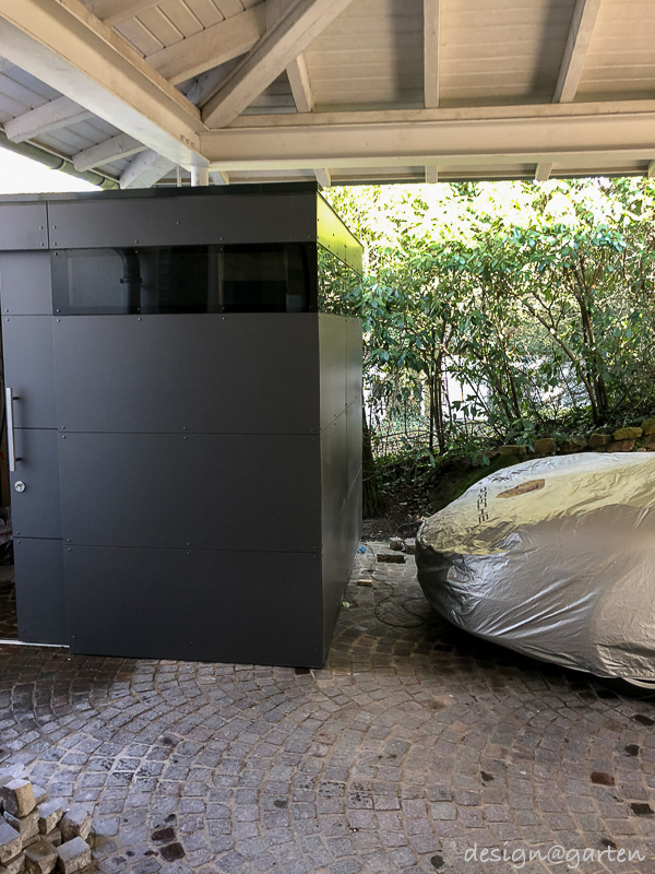 Lavoro su misura sotto il posto auto coperto: la casetta da giardino di design come miracolo di integrazione