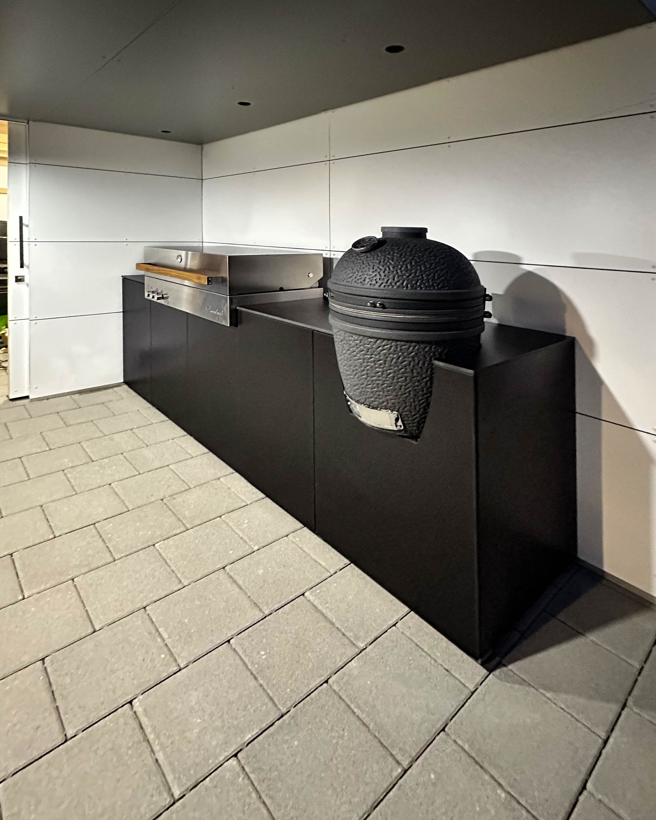 Cucina da esterno nera con grill da incasso Flammkraft e Big Green Egg